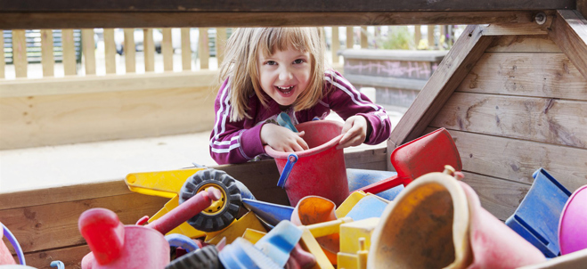 Ett leende barn med sandleksaker.